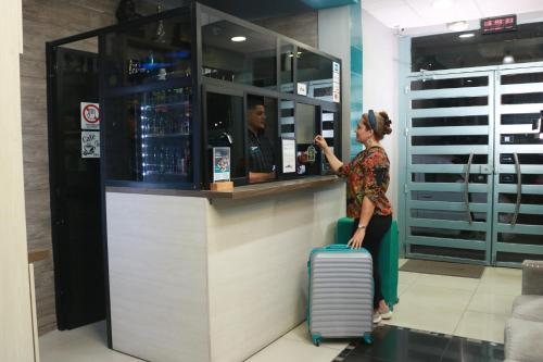 a woman waiting at a bar with her luggage at SUITES FullHouse in Guayaquil