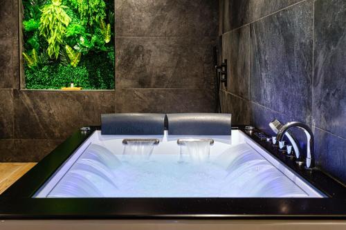 La salle de bains est pourvue d'une baignoire et d'un lavabo. dans l'établissement Le SPA & Le Cocon - Jacuzzi - Sauna - Appart'Hôtel SPA - Melina & Alfred Agen, à Agen