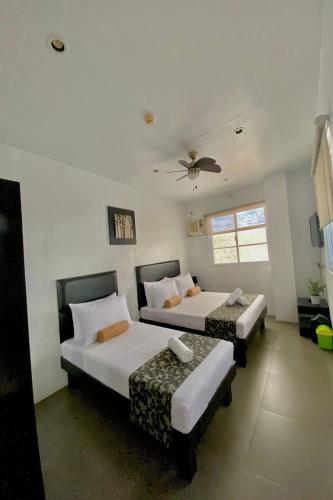 a bedroom with two beds and a ceiling fan at Micasa Lodge Palawan in Coron
