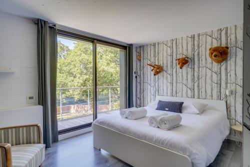 1 dormitorio con cama blanca y ventana grande en Villa La Forêt • Piscine Parking & Wi-Fi, en Sainte-Eulalie