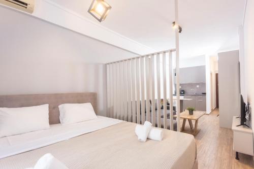 a white bedroom with a bed and a balcony at Downtown Seaside Studios in Thessaloniki