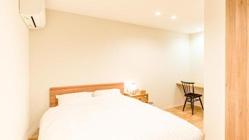 a bedroom with a white bed and a chair at Rakuten STAY HOUSE x WILL STYLE Yufuin Kawakami in Yufu