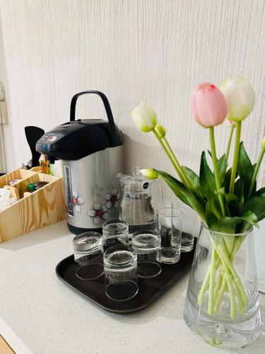 a vase with flowers and glasses on a counter at Phuong Nam Hotel An Giang in Long Xuyên