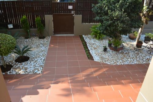 a garden with a brick walkway and trees and rocks at GuestHouse 1109 in Maputo