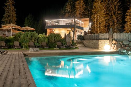 a swimming pool at night with a house in the background at Croce Bianca Leisure & Spa Hotel in Canazei