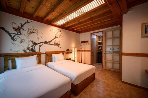 a bedroom with two beds and a painting on the wall at Jeonju Wangyijimil Hanok Hotel in Jeonju