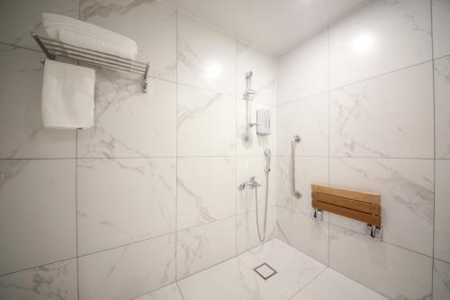 a white bathroom with a shower and a bench at Busan H-AVENUE Hotel Seomyeon Station in Busan