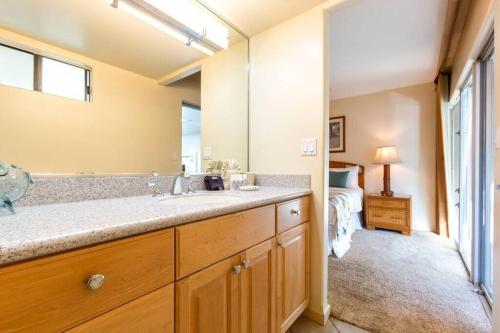 a bathroom with a sink and a large mirror at Hololani B603- Beautiful ocean views at this 2 bedroom condo in Kahana