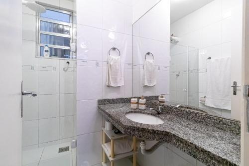 ein weißes Bad mit einem Waschbecken und einer Dusche in der Unterkunft Girl From Ipanema Apartment in Rio de Janeiro