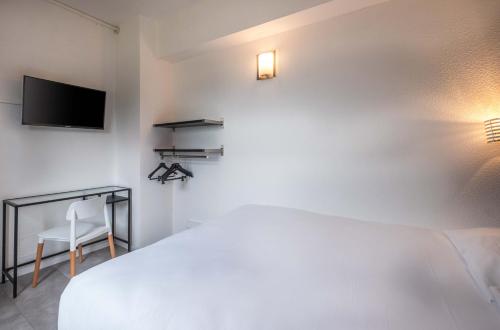 a bedroom with a bed and a tv and a chair at The Originals City, Hotel Ariane, Toulouse Sud Labège in Toulouse
