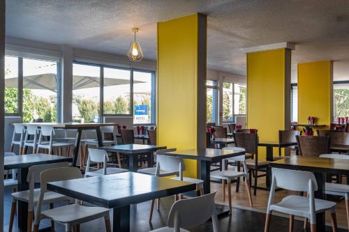 The Originals City, Hotel Ariane, Toulouse في تولوز: غرفة طعام بها طاولات وكراسي وجدران صفراء
