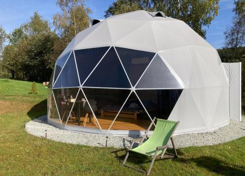 a dome tent with a green chair in the grass at Poziom 713 in Trzebunia