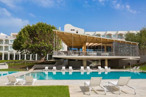a resort with a swimming pool with chairs and a building at OZADI Tavira Hotel in Tavira