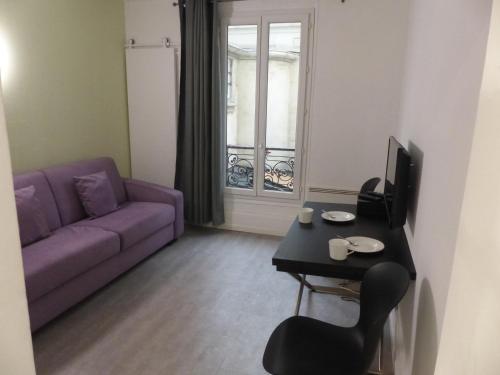 un salon avec un canapé violet et une table dans l'établissement Charmant logement près Parc Buttes Chaumont, à Paris