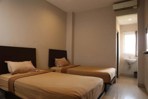 a hotel room with two beds and a sink at Bale Ocasa by Behomy in Tangerang
