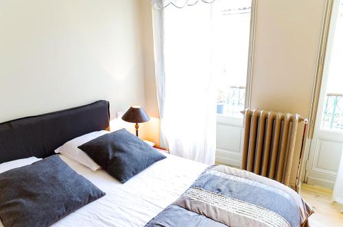 a bedroom with a bed with blue pillows and a window at Turenne - Appartement 1 chambre proche du Jardin Public in Bordeaux