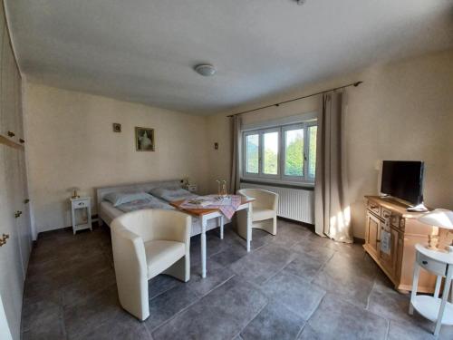 a living room with a table and chairs and a television at Villa Romy mit 3 Gästezimmer in Bad Ischl