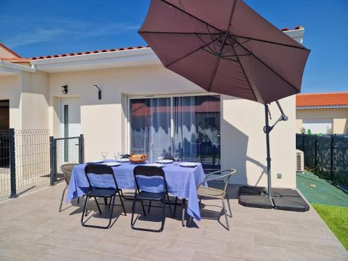 stół z krzesłami i parasol na patio w obiekcie Le Brasil - Maison 74 m - Calme avec terrasse Sud classée 3 étoiles w mieście Le Boulou
