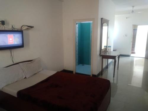 1 dormitorio con 1 cama y TV en la pared en MYSORE MAHALAKSHMI ROOMS en Mysore