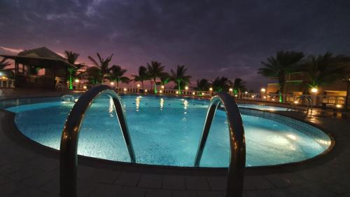 una grande piscina notturna con luci di منتجع شاطئ الدولفين للإيواء السياحي a Yanbu
