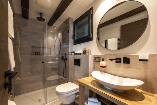 ein Badezimmer mit einem Waschbecken, einem WC und einem Spiegel in der Unterkunft The Cottage by SCHLOSS Zermatt in Zermatt