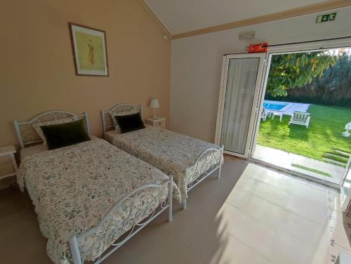 a bedroom with two beds and a large window at Quinta Camargue in Cela Velha