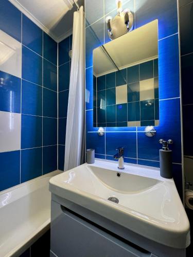 a blue tiled bathroom with a sink and a tub at Your cozy place in Târgu-Mureş