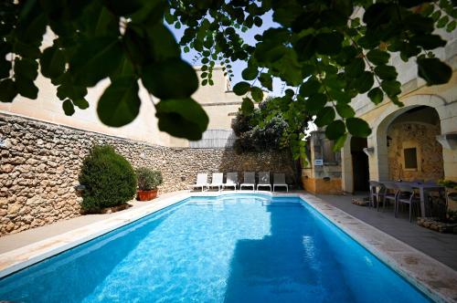 a swimming pool with chairs and a building at Ta'Filomena in Xagħra