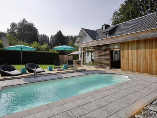 - une piscine avec 2 chaises longues et 2 parasols dans l'établissement Plushy Holiday Home in Spa with bubble bath Pool, à Spa