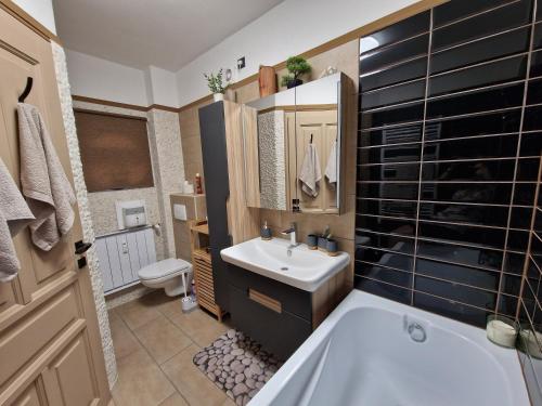 een badkamer met een wit bad en een wastafel bij Rozina Apartman in Mosonmagyaróvár
