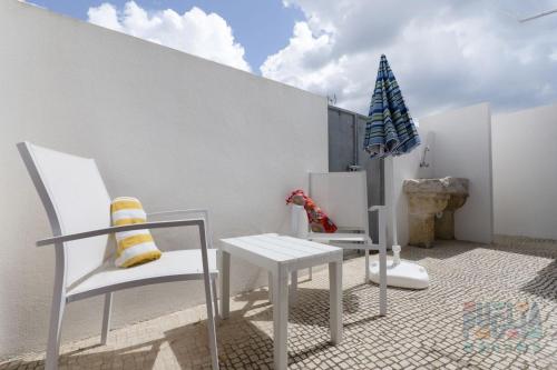 eine Terrasse mit 2 Stühlen, einem Tisch und einem Sonnenschirm in der Unterkunft Villetta Daversa 1 in Torre Vado