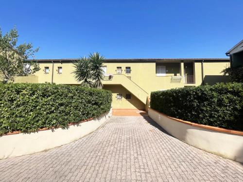 a brick walkway leading to a building with bushes at Bagnaia Lido 16 - ArgonautiVacanze in Portoferraio