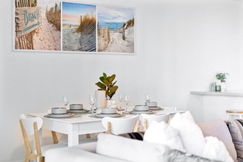 a white dining room with a white table and chairs at Wings Apartments - QStay in Gold Coast