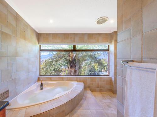 a large bathroom with a tub and a large window at Aan de Paarlberg in Paarl