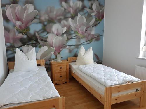 two beds in a room with a mural of flowers at Ferienwohnung am Viaduktweg Familie Roman in Langenleuba-Niederhain