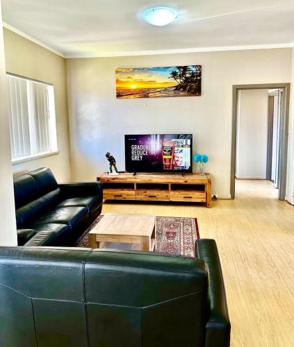 a living room with a black leather couch and a flat screen tv at Kalgoorlie Accommodation in Kalgoorlie