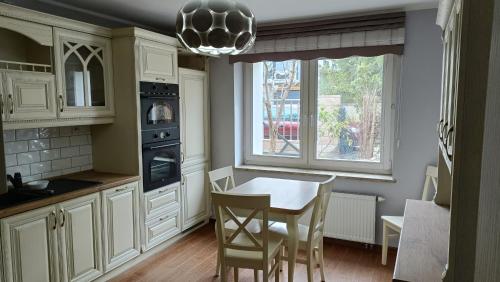 a kitchen with white cabinets and a table and a window at Pokoje nad jeziorem Gdańsk in Gdańsk