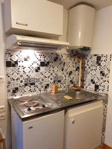 Il dispose d'une cuisine avec une cuisinière et un mur en carrelage. dans l'établissement Ancienne échoppe à deux pas de la cathédrale, à Saint-Flour