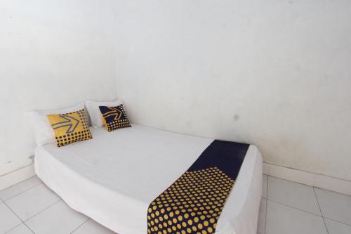 a white couch with two pillows and a tie on it at OYO Life 93153 Kos Jenggala in Tanjung