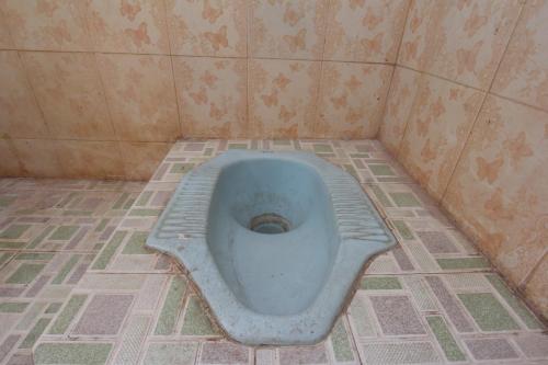 a bathroom with a blue toilet in a tiled floor at OYO Life 93153 Kos Jenggala in Tanjung