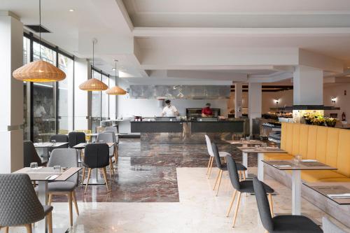 a restaurant with tables and chairs and a chef in the kitchen at AluaSoul Orotava Valley - Adults Only in Puerto de la Cruz