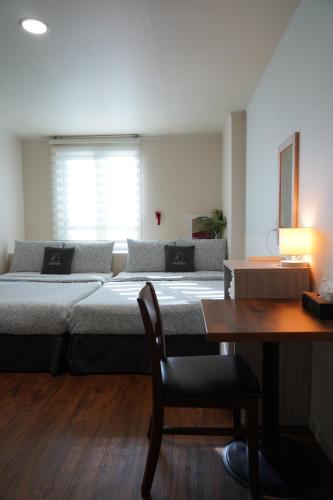 a large bed in a room with a table and a desk at Seoul Grand Hostel EWHA Univ in Seoul