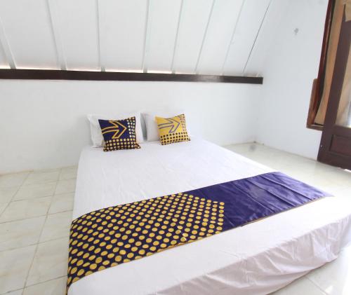 Schlafzimmer mit einem Bett mit gelben und blauen Kissen in der Unterkunft OYO Life 93154 White Kos Jenggala in Tanjung