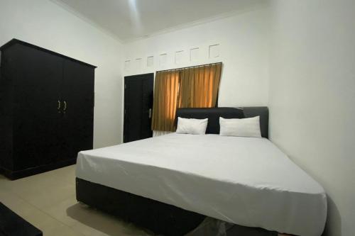 een slaapkamer met een groot bed met witte lakens bij OYO Life 93156 Rumah Kosan in Tanjung