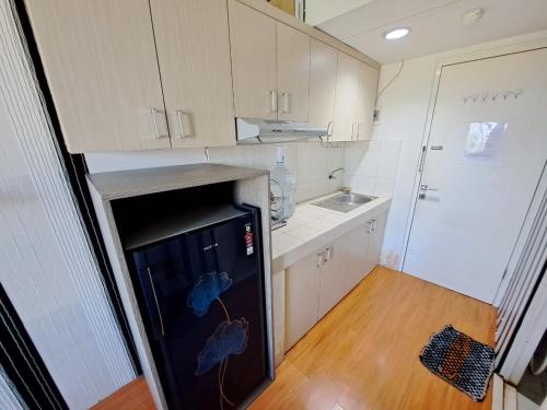 eine kleine Küche mit einem schwarzen Kühlschrank und einer Spüle in der Unterkunft OYO Life 93106 Apartement Grand Sentraland By Andi in Karawang