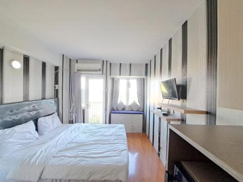 Schlafzimmer mit einem Bett, einem Schreibtisch und einem TV in der Unterkunft OYO Life 93106 Apartement Grand Sentraland By Andi in Karawang