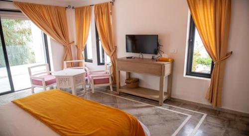 um quarto com uma cama e uma secretária com uma televisão em Dar Gino em Kelibia