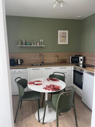 een keuken met een witte tafel en stoelen en een tafel en een magnetron bij Appartement comme à la maison refait à neuf in Boulogne-sur-Mer