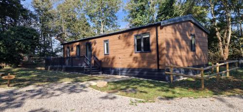 a small wooden cabin with a fence in a yard at Woolverstone Marina and Lodge Park in Ipswich