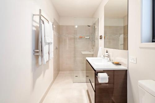 baño blanco con ducha y lavamanos en Oceana B&B, en Howrah